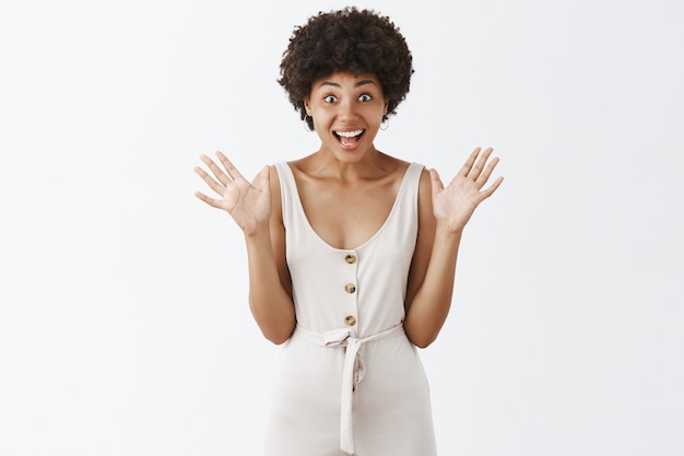 Photo gratuite fille élégante surprise et impressionnée posant contre le mur blanc