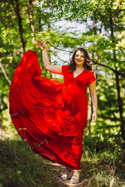 Photo gratuite la fille enceinte qui marche le long de la forêt