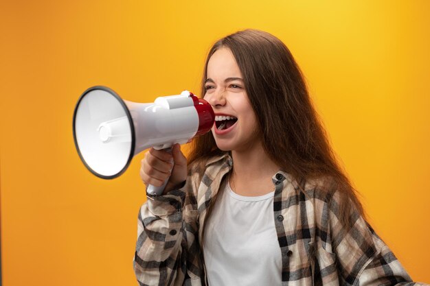 Fille enfant à l'aide d'un mégaphone sur fond jaune