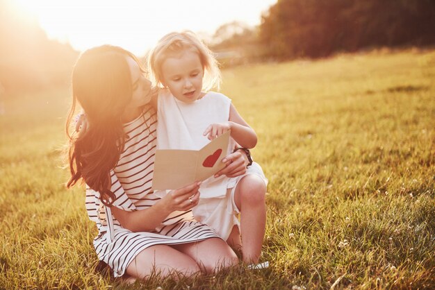 La fille de l'enfant félicite sa mère et lui donne une carte postale.