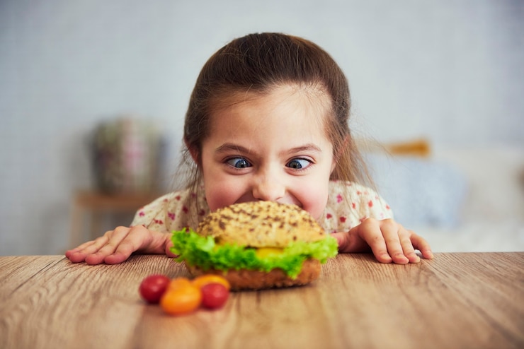 Photo gratuit une fille enjouée qui regarde un délicieux hamburger.