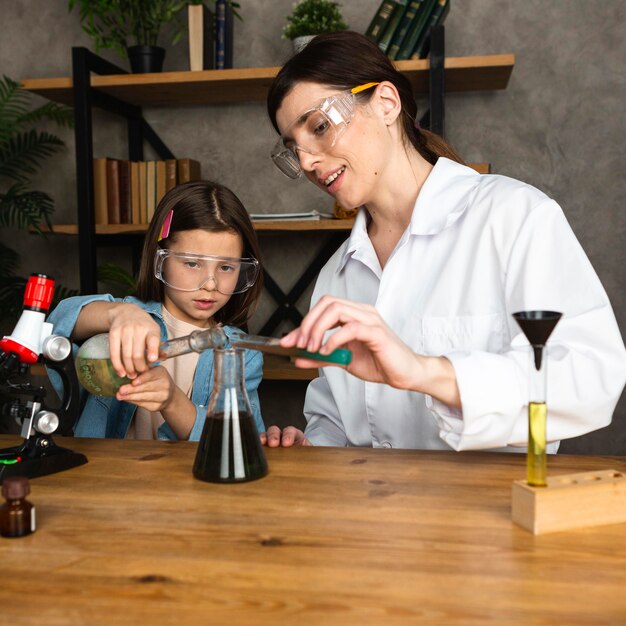 Fille et enseignante faisant des expériences scientifiques au microscope