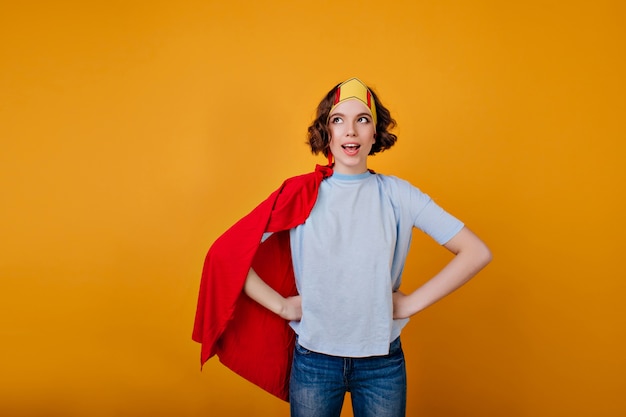 Fille enthousiaste avec une coiffure frisée posant en manteau rouge