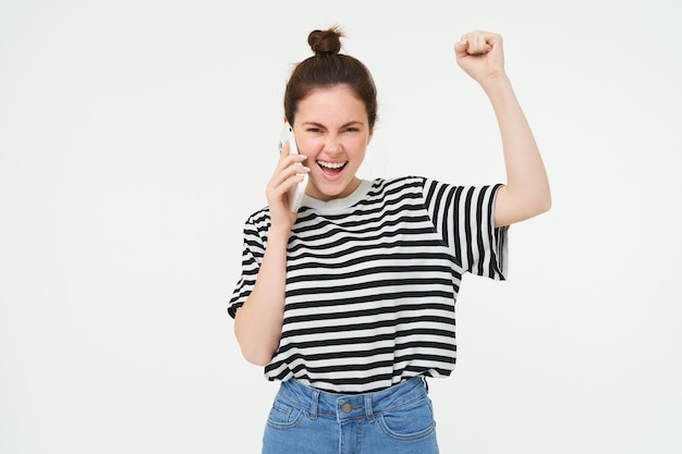 Une fille enthousiaste répond à un appel téléphonique et semble excitée triomphant de grands stands de nouvelles.