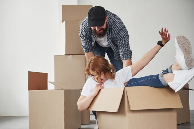 La fille est à l'intérieur de la boîte. Heureux couple ensemble dans leur nouvelle maison. Conception du déménagement