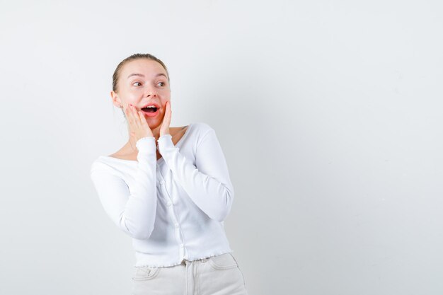 La fille étonnée regarde quelqu'un sur le fond blanc