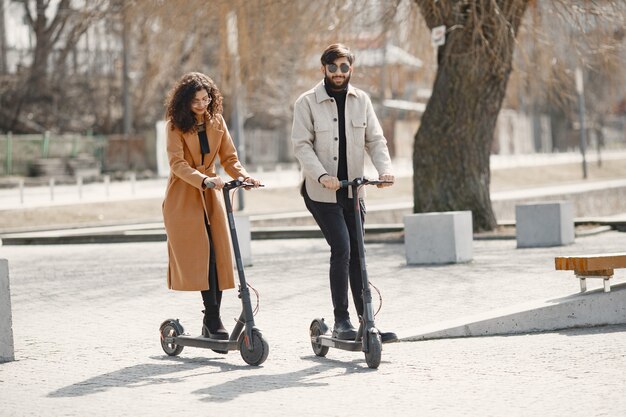 Fille européenne anindian guy monter des scooters et sourire.