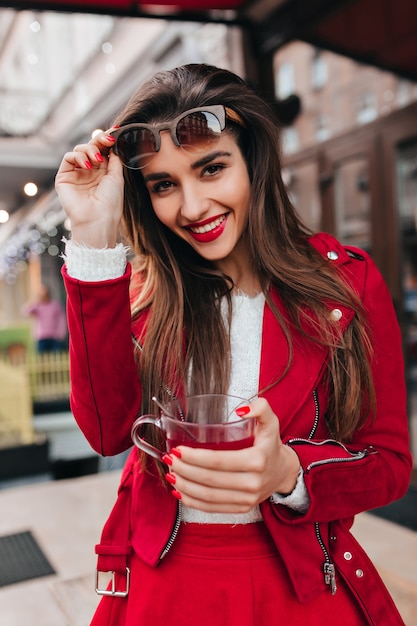 Fille européenne inspirée avec un maquillage lumineux riant sur l'espace urbain