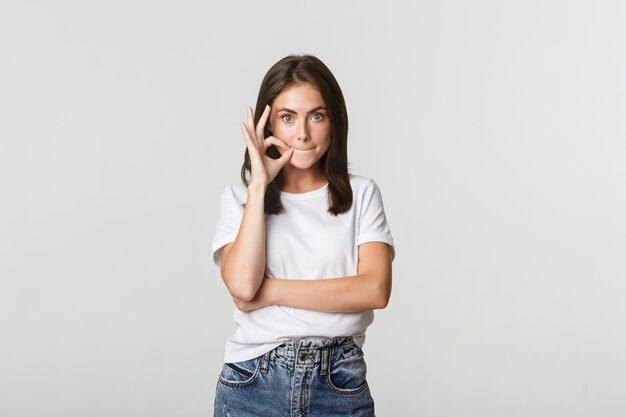 Fille excitée bavardant, fermant la bouche, gardant le secret.