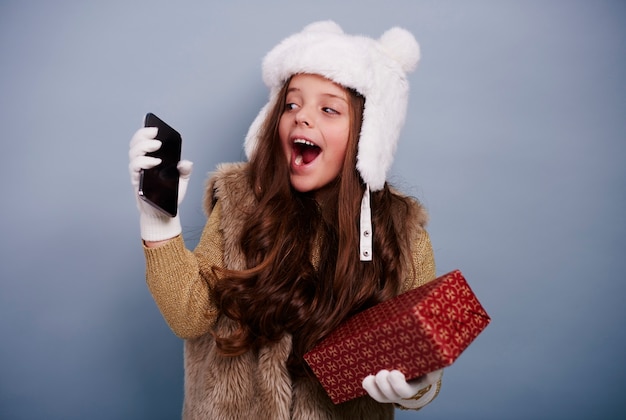 Fille excitée avec téléphone portable et boîte-cadeau