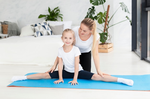 Fille exerçant avec la mère à la maison