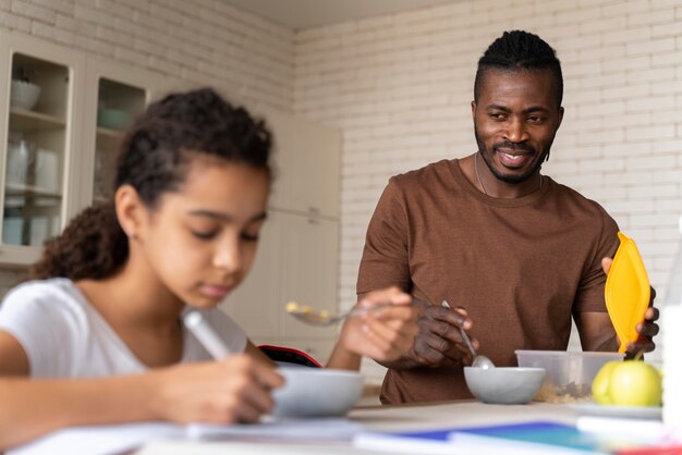 Fille faisant ses devoirs tout en prenant son petit déjeuner