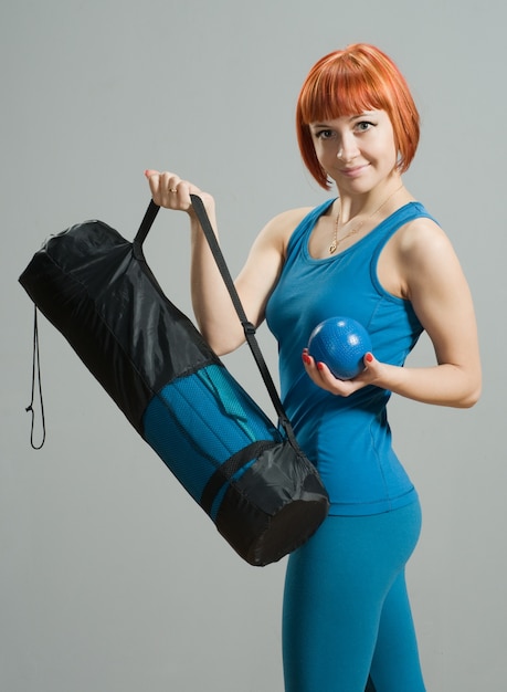 Fille de fitness aux cheveux roux avec tapis de yoga