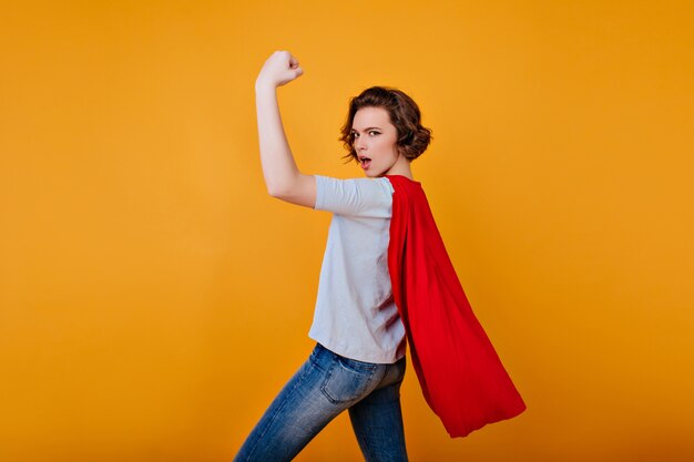 Fille forte en pantalon en denim et t-shirt bleu posant avec la main