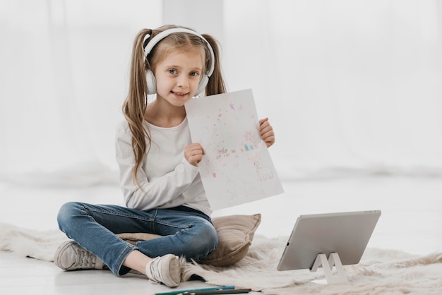 Fille fréquentant des cours virtuels et tenant un dessin