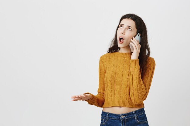 Fille frustrée se disputant sur appel téléphonique, parlant et roulant des yeux bouleversés, levant les yeux et se plaignant