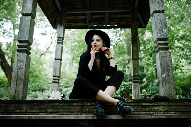 Fille de fumeur sensuelle tout en lèvres rouges noires et chapeau Goth dramatique femme fumant une cigarette mince