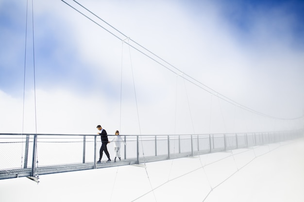 Fille et garçon marchant sur le pont dans les nuages