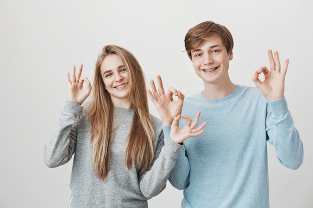 Fille et gars montrant un signe correct. Les frères et sœurs vous assurent et souriant