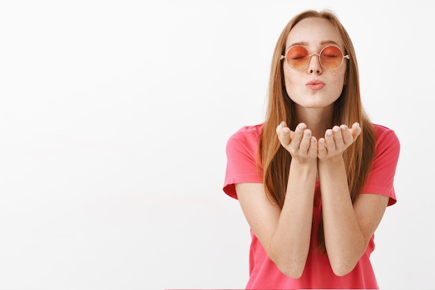 fille de gingembre européenne calme et tendre paisible avec des taches de rousseur fermant les yeux pliant les lèvres et soufflant baiser exprimant l'amour passion et romance