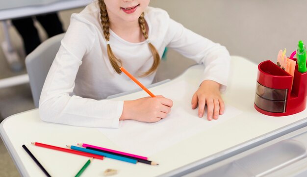 Fille de grand angle écrit sur un cahier vide