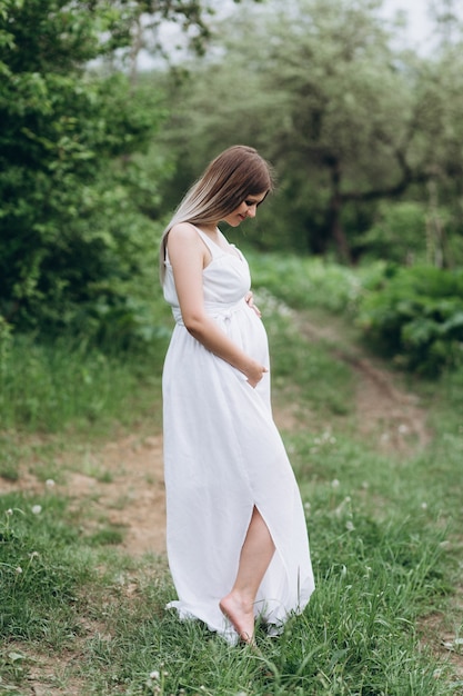 La fille de grossesse se tient sur l&#39;herbe