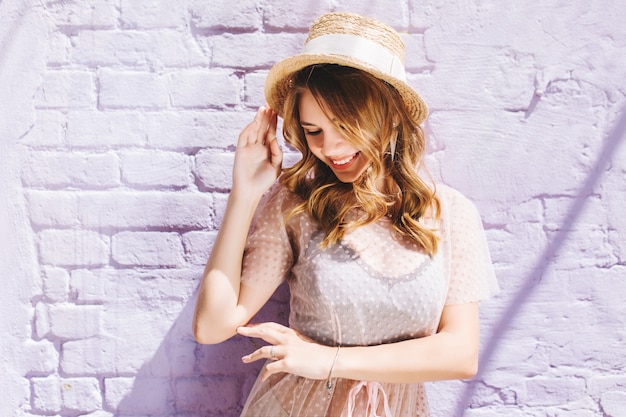 Photo gratuite fille heureuse au chapeau de paille vintage avec ruban blanc posant avec un sourire heureux et les yeux fermés