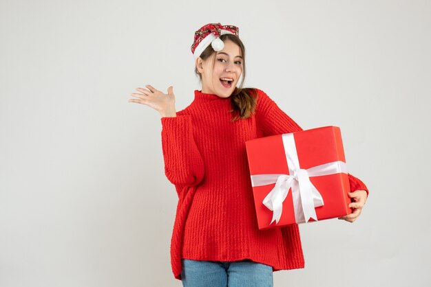 fille heureuse avec bonnet de noel tenant une boîte cadeau debout sur blanc