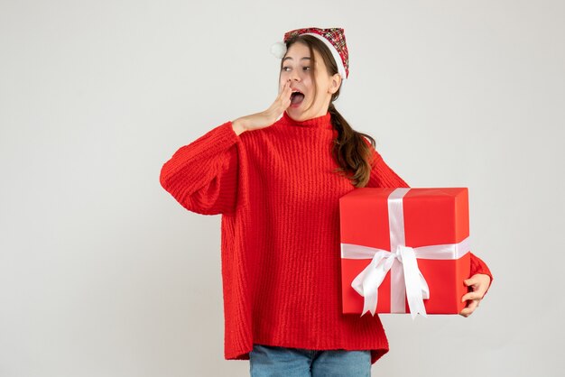 fille heureuse avec bonnet de noel tenant un cadeau sur blanc