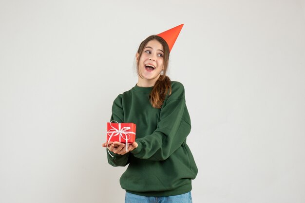 fille heureuse avec chapeau de fête montrant son cadeau de Noël sur blanc