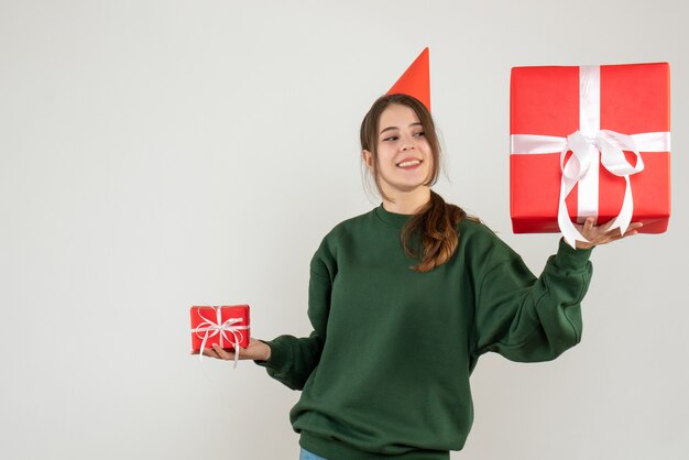 fille heureuse avec chapeau de fête vérifiant ses cadeaux de Noël sur blanc