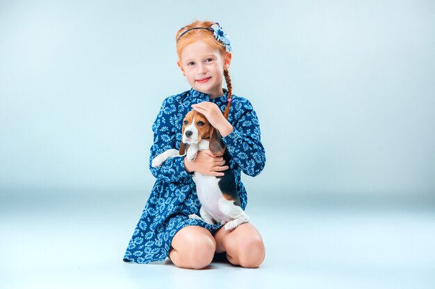 La fille heureuse et un chiot beagle sur fond gris