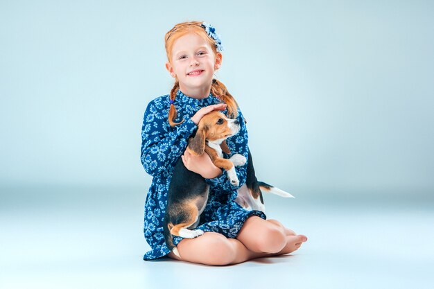 La fille heureuse et un chiot beagle sur mur gris