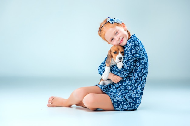 La fille heureuse et un chiot beagle sur mur gris