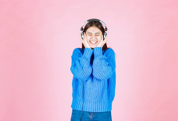 fille heureuse dans les écouteurs debout sur le rose.