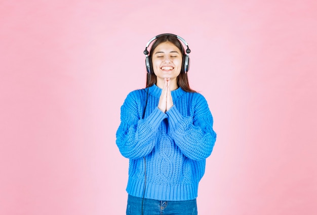 fille heureuse dans les écouteurs debout sur le rose.