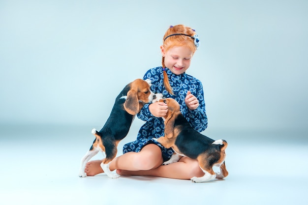 La fille heureuse et deux chiot beagle sur mur gris