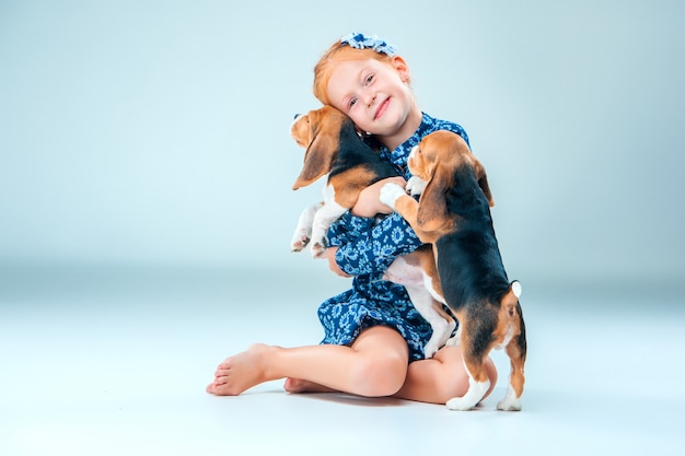 fille heureuse et deux chiots beagle sur gris