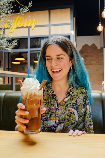 Fille heureuse avec un grand milk-shake au chocolat dans un café