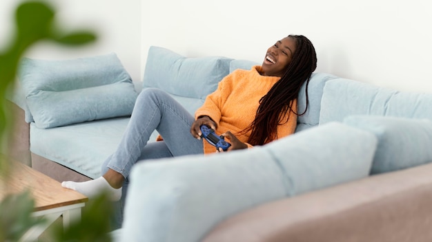 Photo gratuite fille heureuse jouant au jeu vidéo sur le canapé