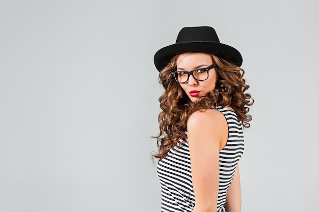 La Fille Heureuse à Lunettes Et Chapeau Sur Fond Gris