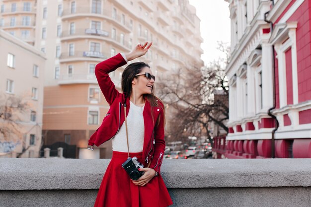 Fille heureuse à lunettes dansant dans la rue après une séance photo