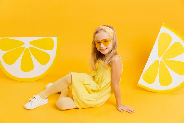 Fille heureuse avec des lunettes de soleil posant avec des décorations de tranches de citron