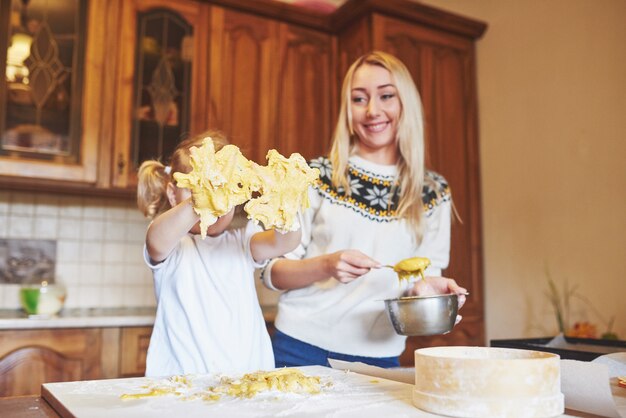 Fille heureuse et maman dans la cuisine préparent des biscuits