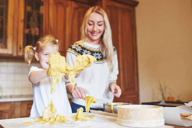 Fille heureuse et maman dans la cuisine préparent des biscuits