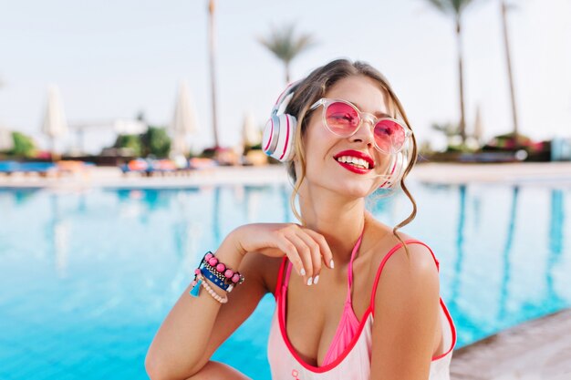 Fille heureuse avec un maquillage lumineux et des accessoires colorés profitant du paysage du sud tout en écoutant de la musique