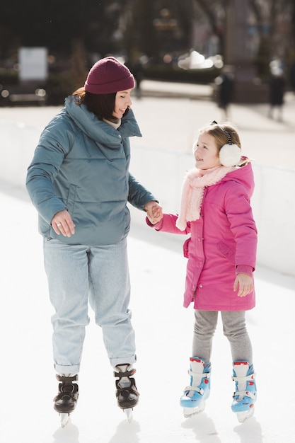 Fille heureuse et mère patinage sur glace