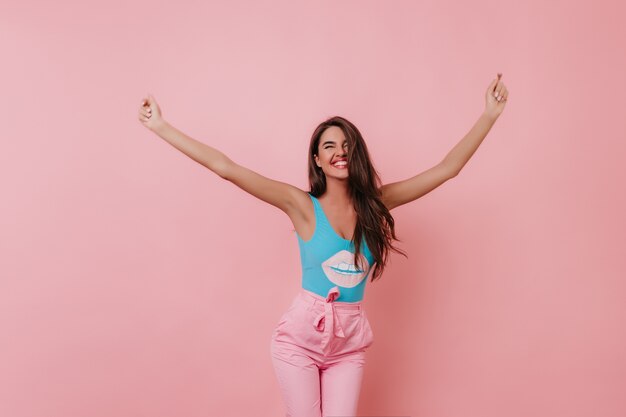 Fille heureuse avec une peau bronzée dansant avec un sourire sincère sur un espace lumineux