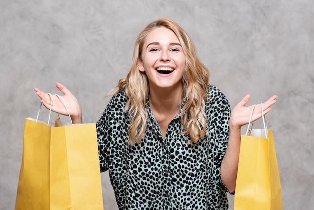 Fille heureuse portant des sacs en papier jaune