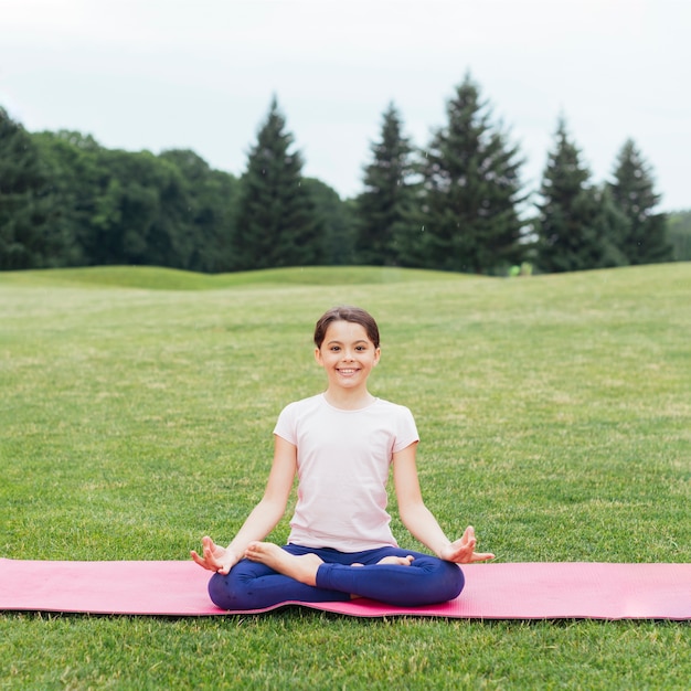 Fille heureuse en position du lotus relaxant dans la nature